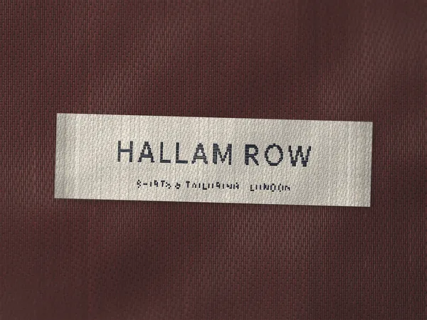 Woven label reading Hallam Row, Shirts and Tailoring, London, navy on cream, on a burgundy lining