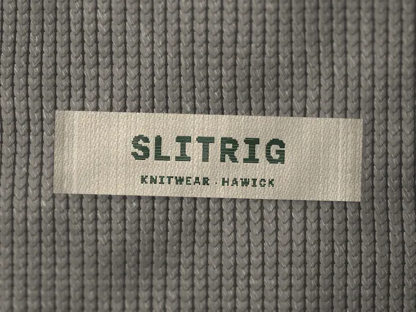 Woven label reading Slitrig, Knitwear, Hawick, stitched inside a grey marl jumper
