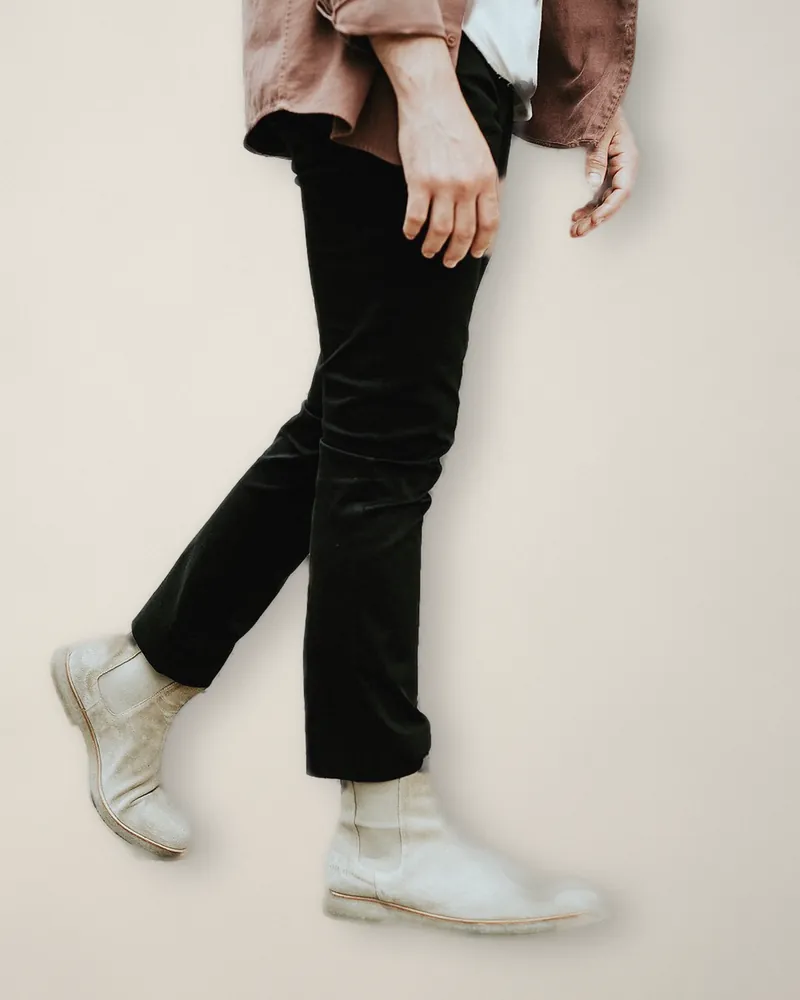 Black cropped flared trousers and pale suede Chelsea boots, mid-stride