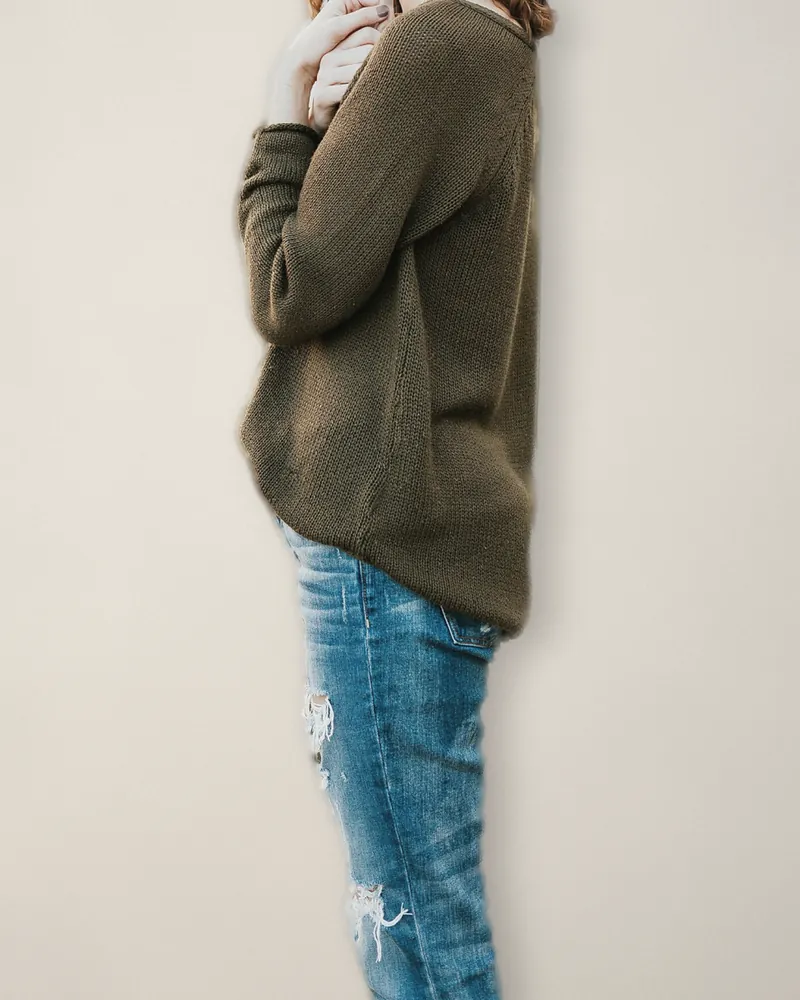 An olive lambswool jumper worn loose over faded jeans