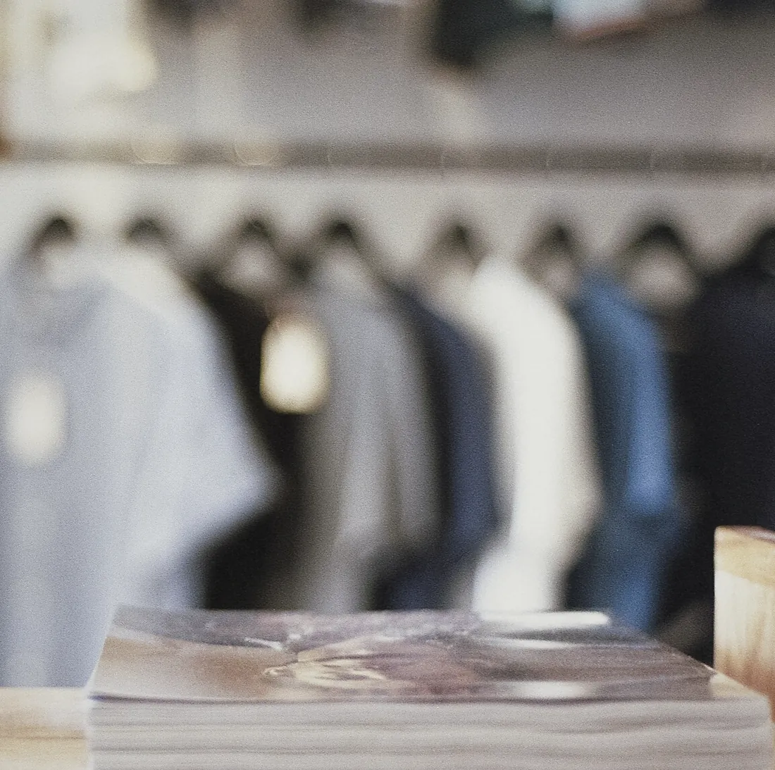 The counter at Odell: this month's magazines on the wood, the shirt rail out of focus behind