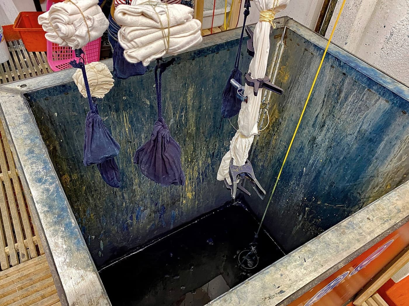 Bundles of cloth hanging into an indigo dye pit