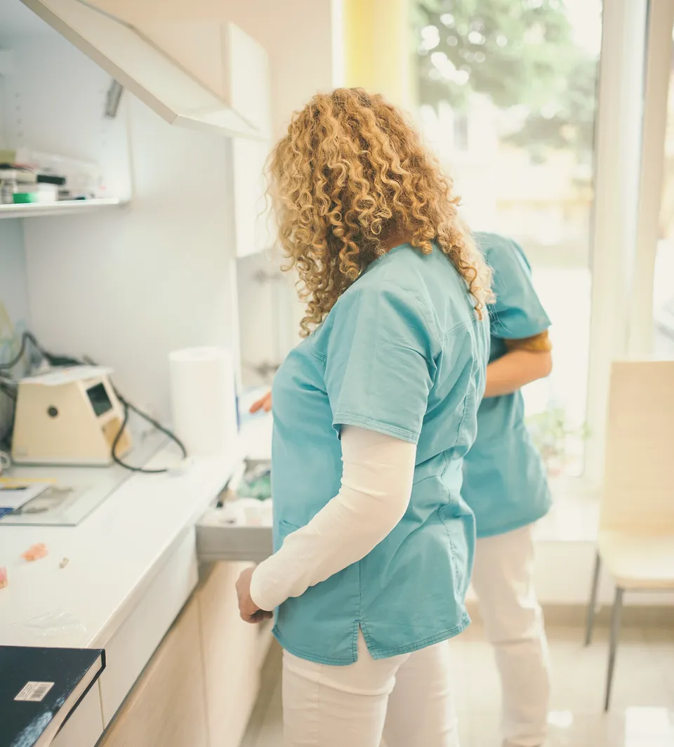 A nurse preparing supplies at the counter of the treatment room.