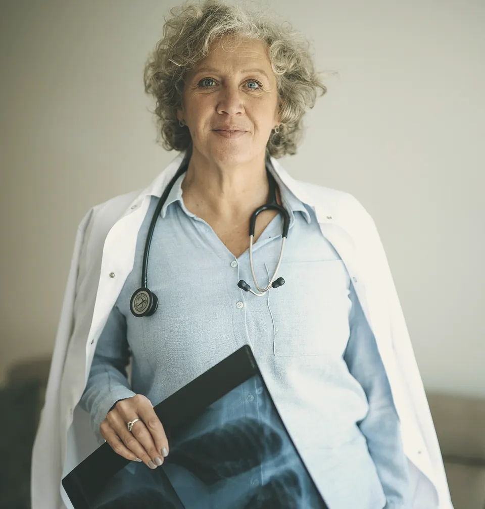 A doctor holding an X-ray film in her consulting room.