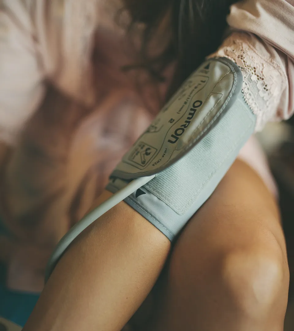 A blood pressure cuff fastened round a woman's upper arm.