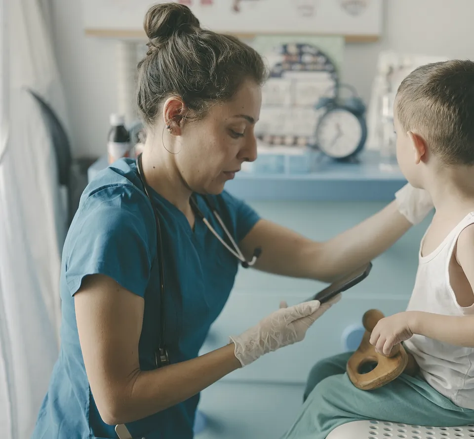 Jo Mercer, practice nurse, checking a young boy sitting on a chair.