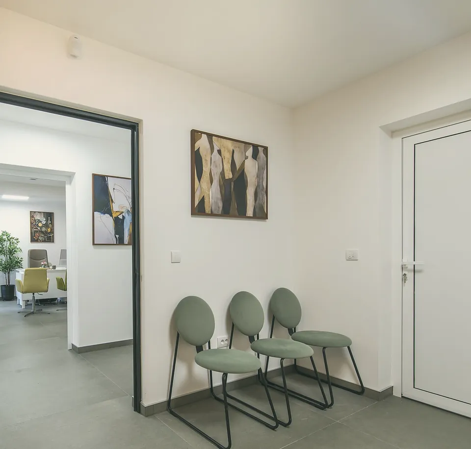 Sage-green chairs outside an open consulting-room door.