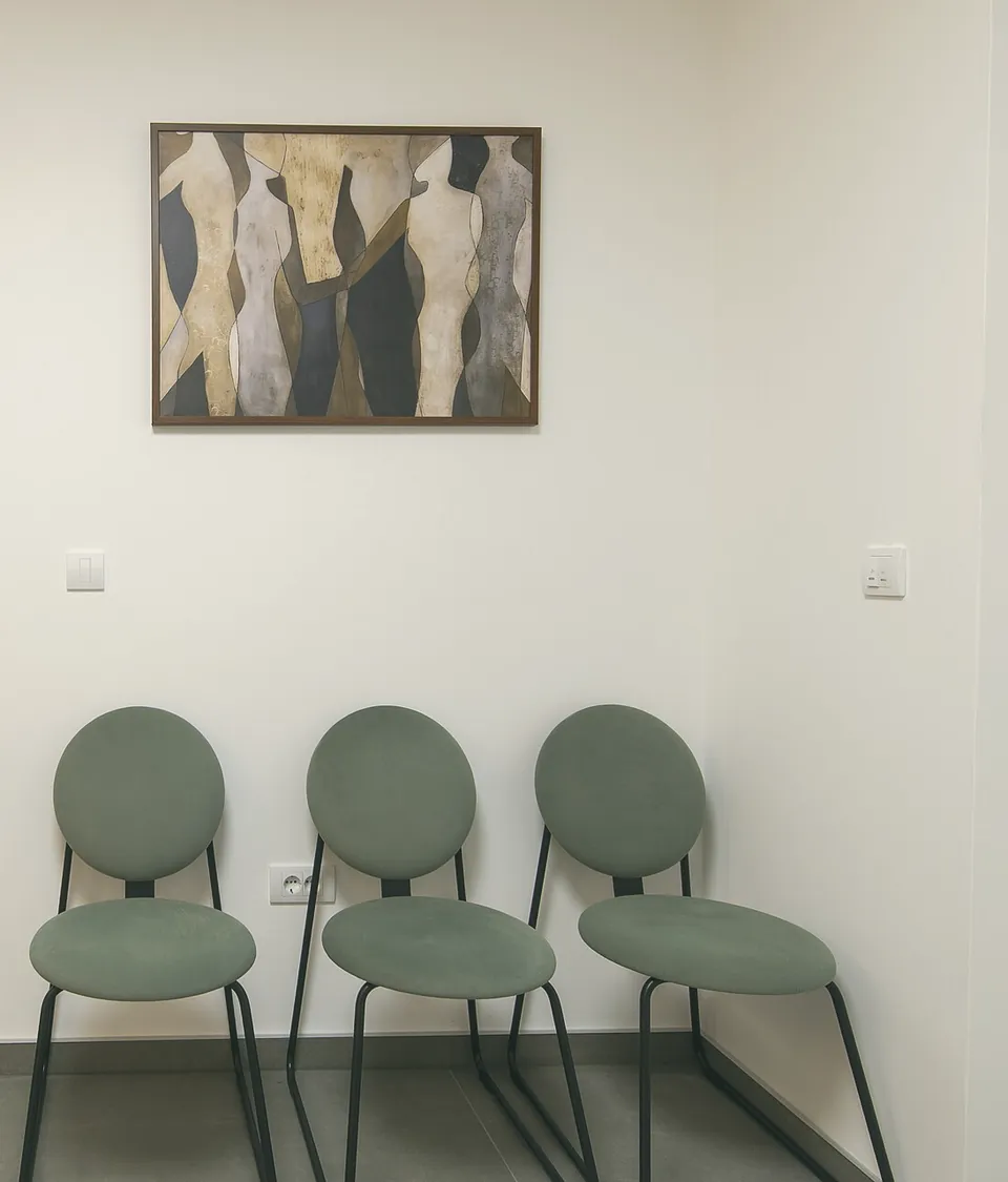 Three sage-green chairs under a painting in the waiting room.