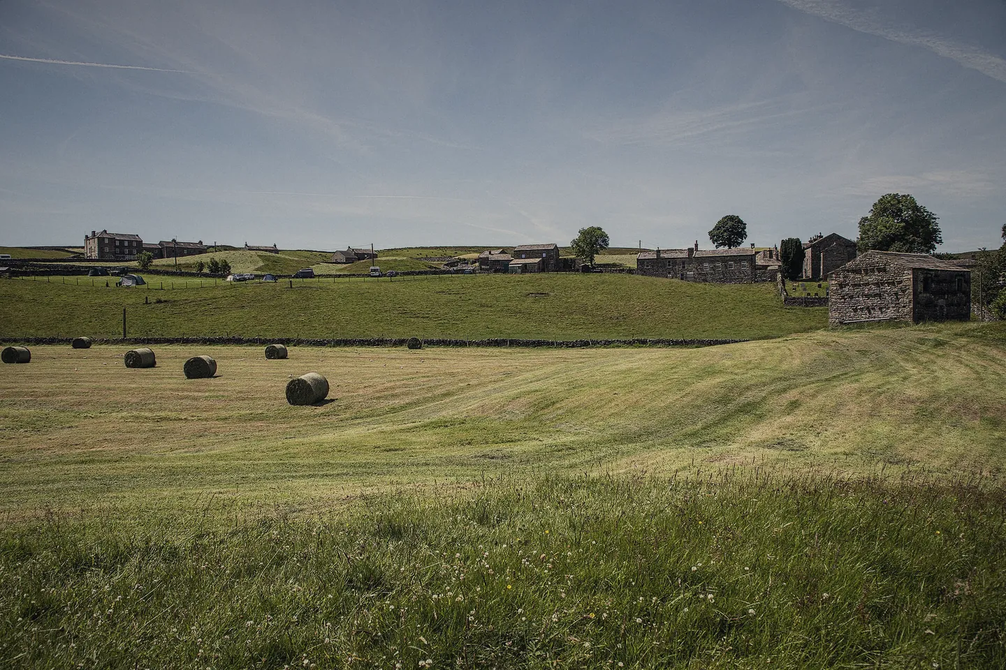 Round bales drying in a cut meadow, Keld and its barns behind