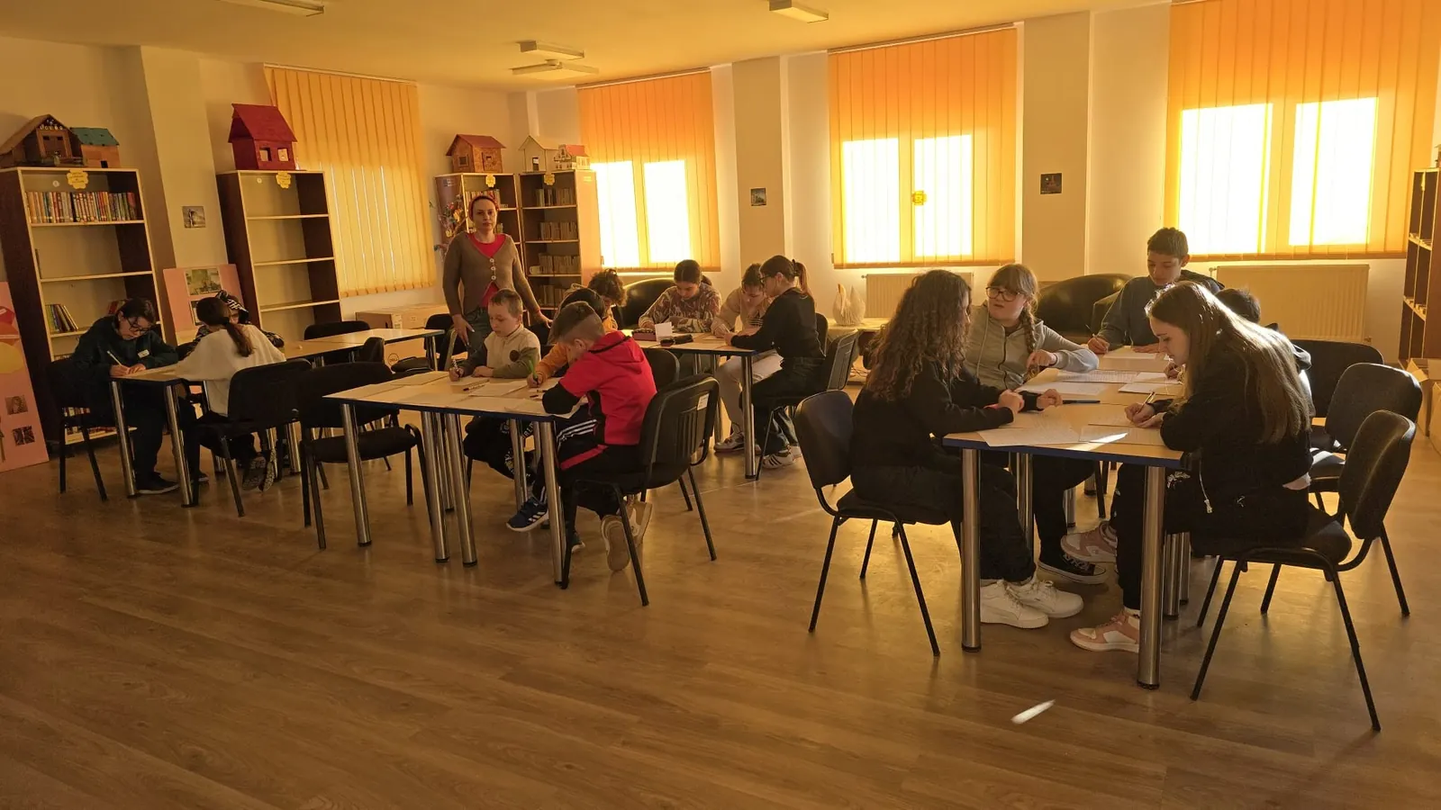 Centrul de documentare și informare al școlii: rafturi cu cărți, mese și elevi la lucru