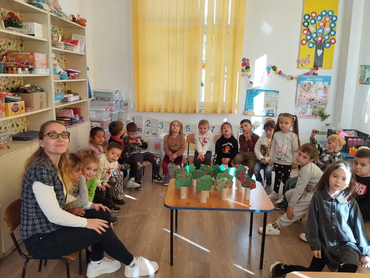 Sala de grupă a grădiniței, preșcolari în cerc cu plante