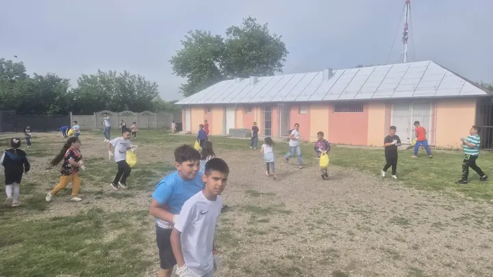Curtea și terenul școlii cu clădirea parter (copii în depărtare, greu identificabili)