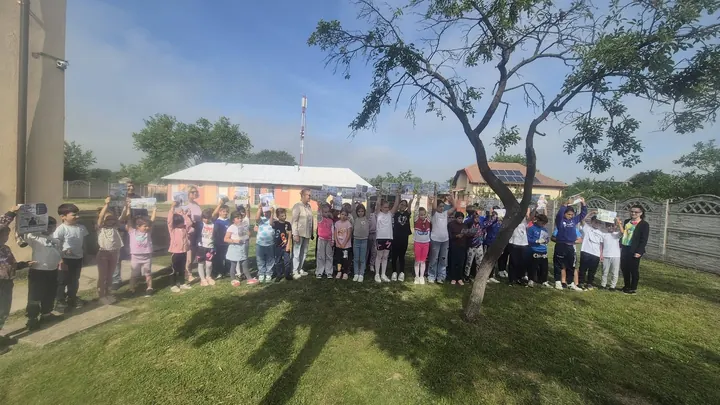 Elevi aliniați în curtea școlii, cu clădirea cu un nivel în fundal; „Micii gardieni ai curățeniei”