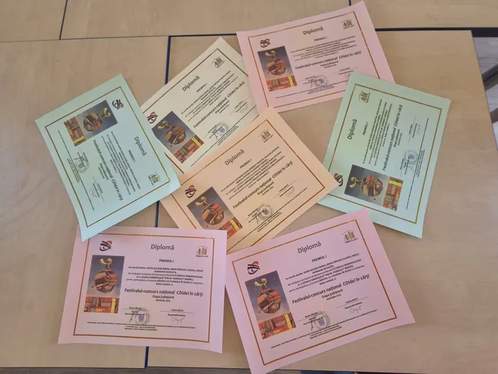 Diplomele obținute la CDIdei în cărți, flat-lay pe masă (fără persoane)