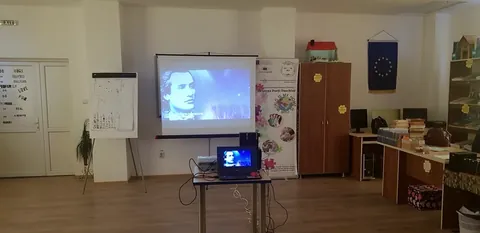 Sala CDI goală, cu o proiecție pe perete și bannere cu steagul Uniunii Europene