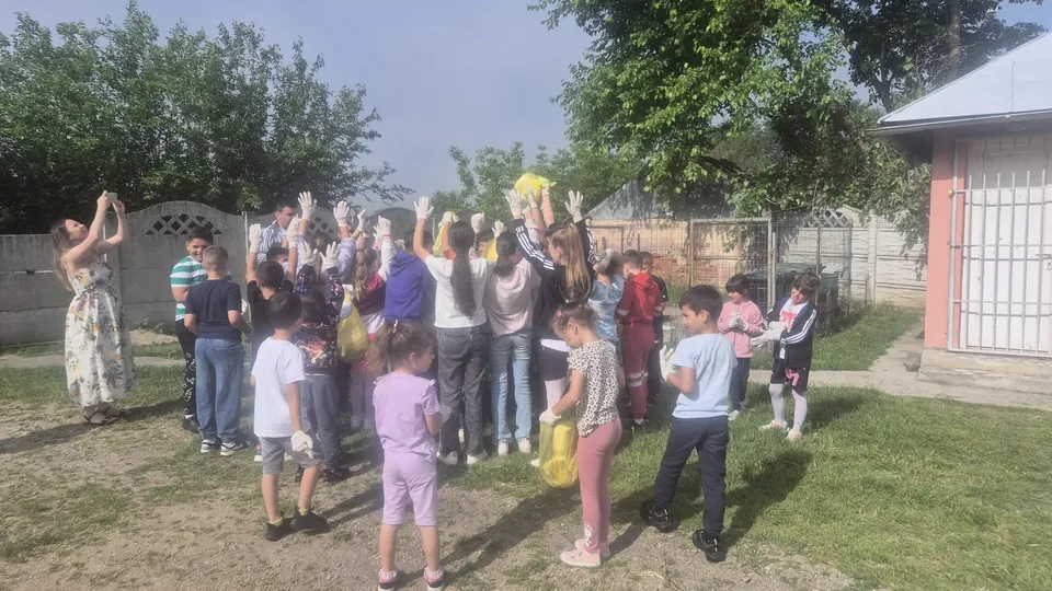 Elevi din ciclul primar în curtea școlii, la o activitate de ecologizare