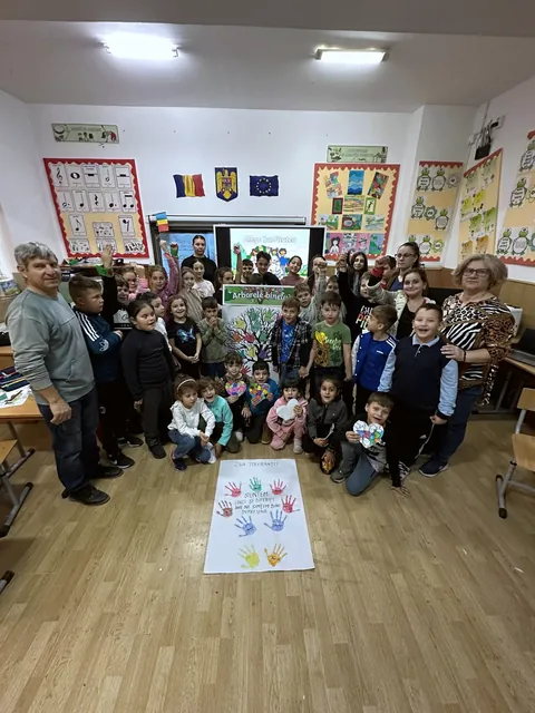 Elevi și profesori în sala mare, lângă panoul cu palme colorate
