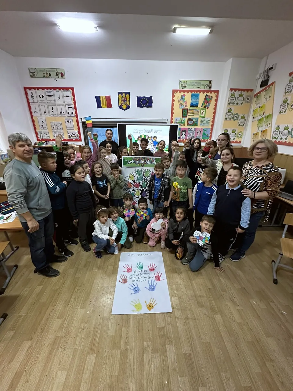 Elevi și profesori în sala mare, lângă panoul cu palme colorate