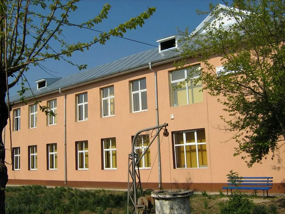 Clădirea școlii din Braneț, cu fântâna din curte, primăvara