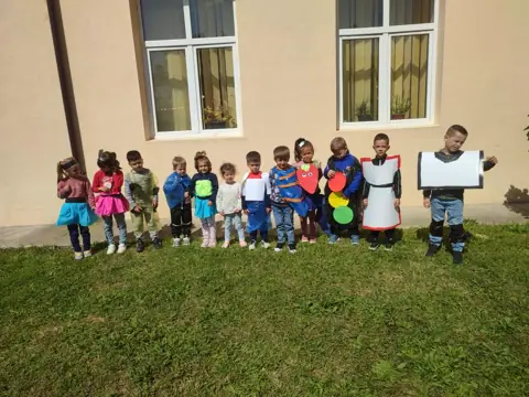 Elevi în costume de semafor/educație rutieră lângă clădirea școlii