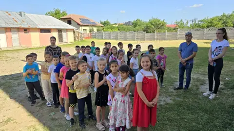 Elevi în curte cu clădirea parter și gardul în fundal
