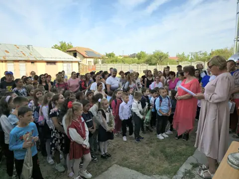 Deschiderea anului școlar 2024, mulțime în curte, clădirea în fundal