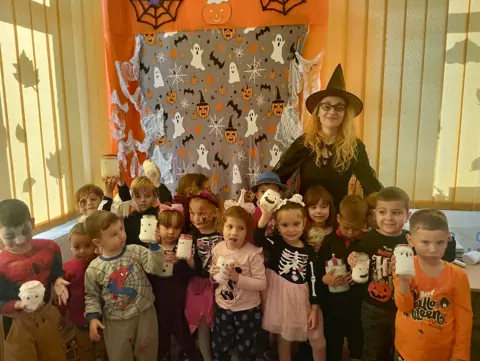 Halloween la grădiniță, educatoare costumată și preșcolari