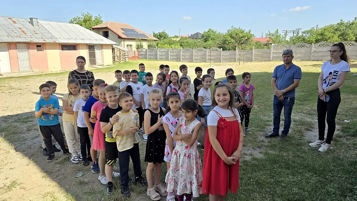 Elevi în curte cu clădirea parter și gardul în fundal