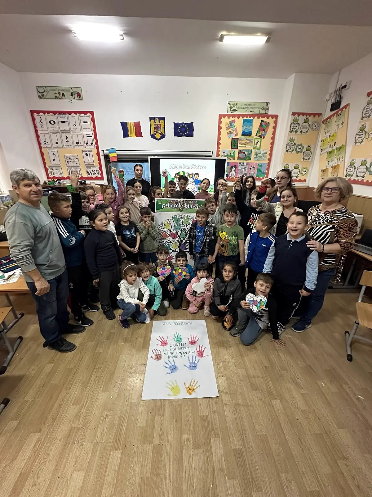 Ziua Internațională a Toleranței 2025, elevi și profesori în sala mare, cu panoul de palme colorate