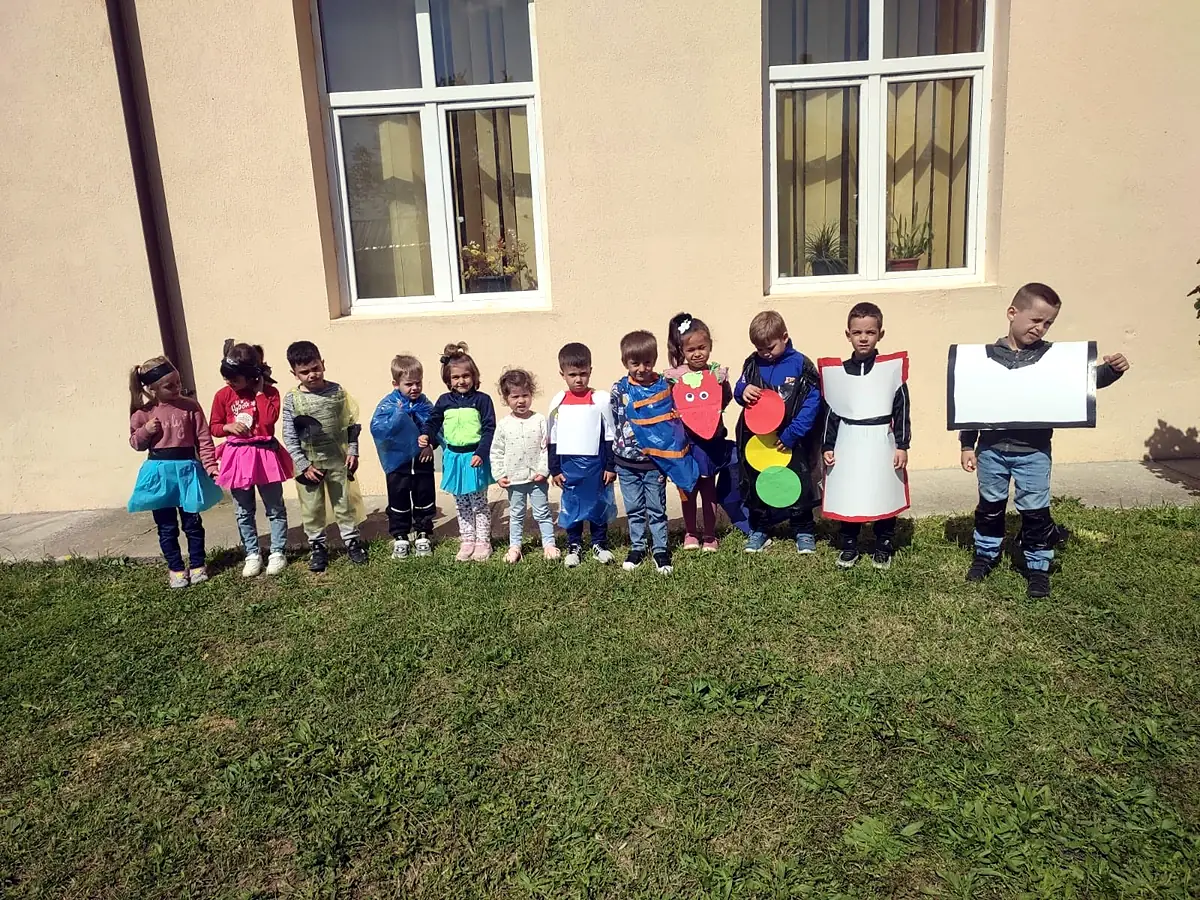 Elevi în costume de semafor/educație rutieră lângă clădirea școlii